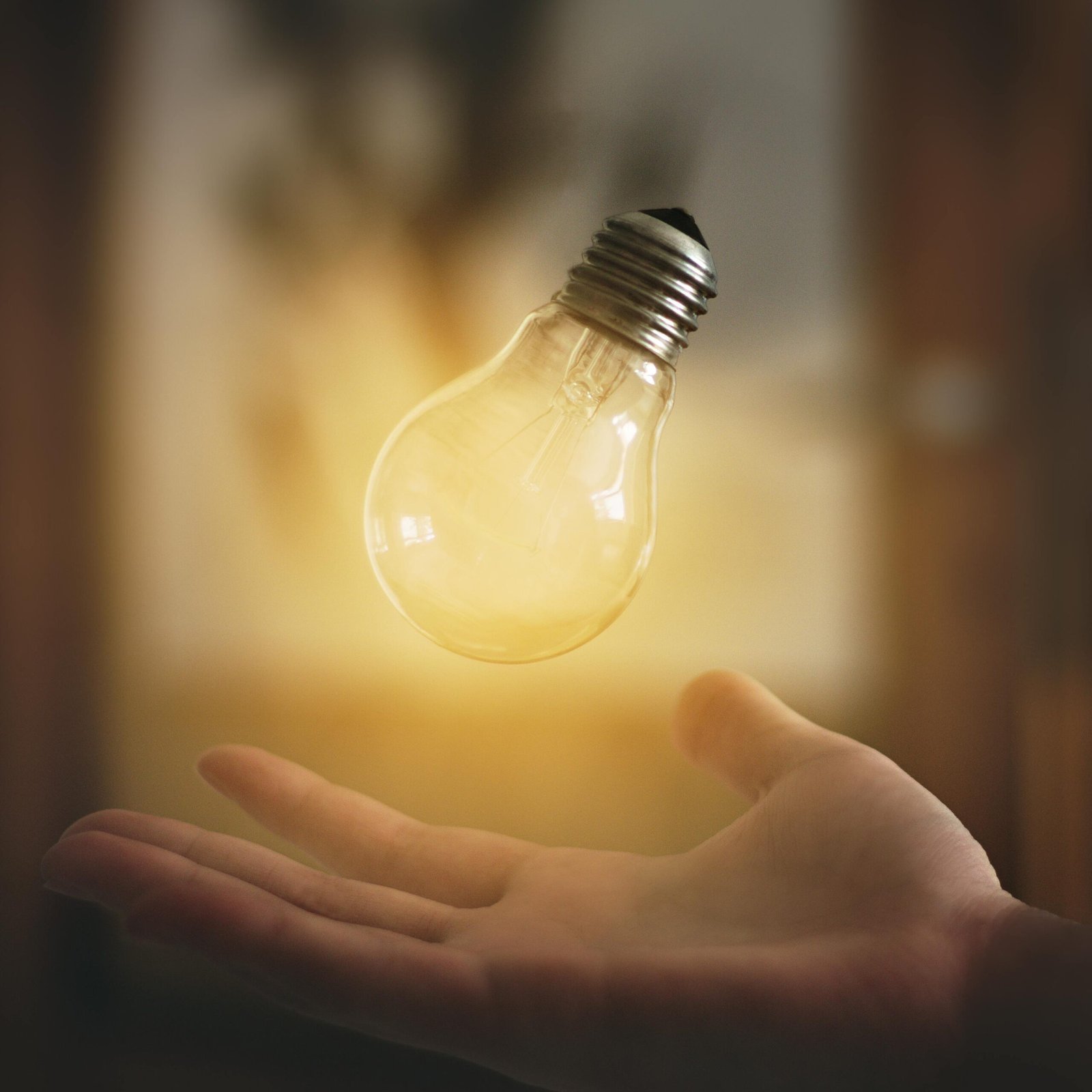 A glowing light bulb hovers above an open hand, symbolizing innovation and creativity.